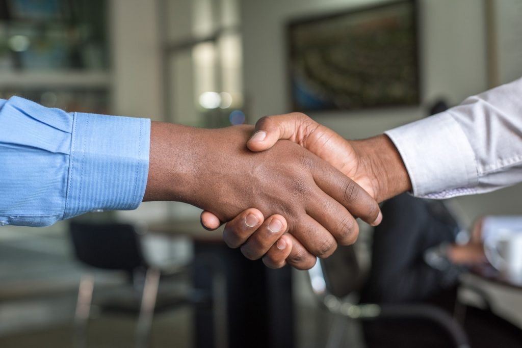 Two businessmen shake hands as a symbolic gesture for a mergers & acquisitions process