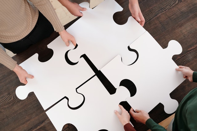 The Mergers & Acquisitions process includes various puzzle pieces, which are symbolized in this picture by four large puzzle pieces