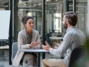 Coaching-Gespräch zwischen einer weiblichen Führungskraft und einem männlichen Coach in moderner Büroumgebung – symbolische Darstellung eines Führungskräfte Coachings im Unternehmenskontext.