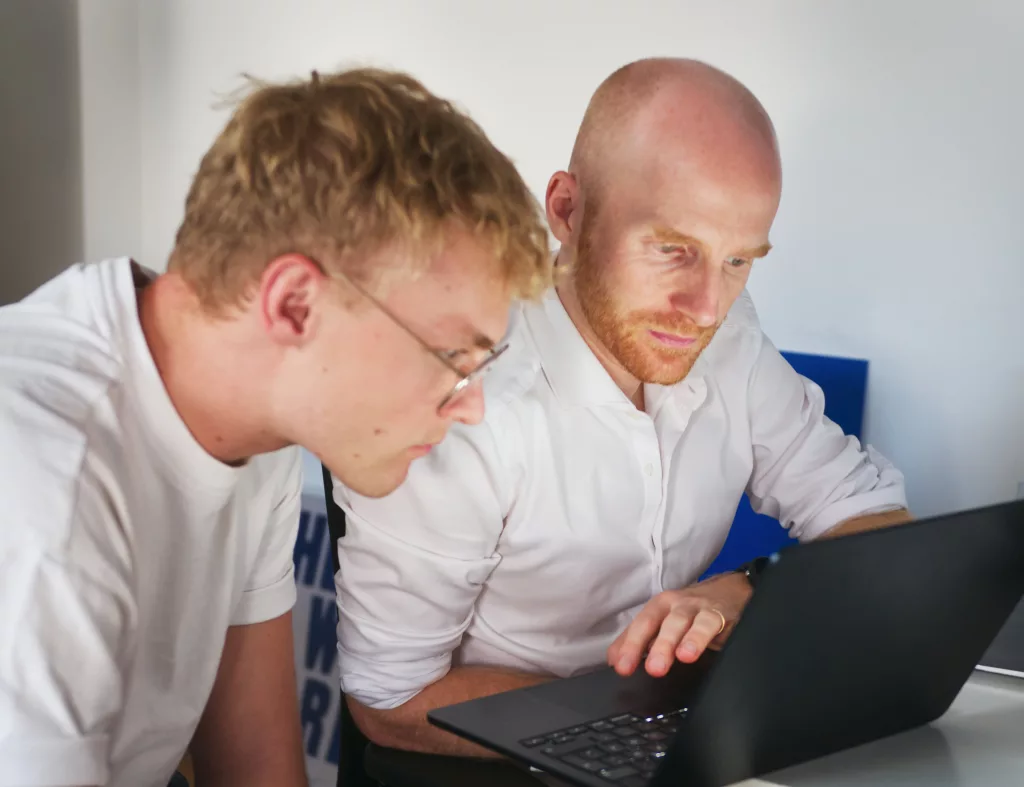 Sparrks Gründer Nicolas Stephan und ein Mitarbeiter arbeiten an einem Laptop