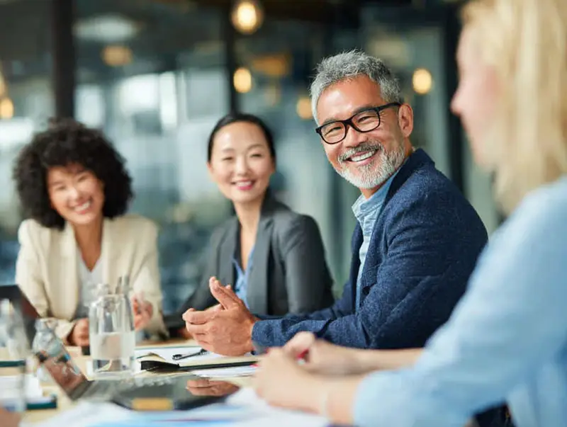 Eine vielfältige Gruppe von Mitarbeitenden diskutiert gemeinsam im Büro symbolisch für inklusive Führung und interkulturelle Zusammenarbeit.